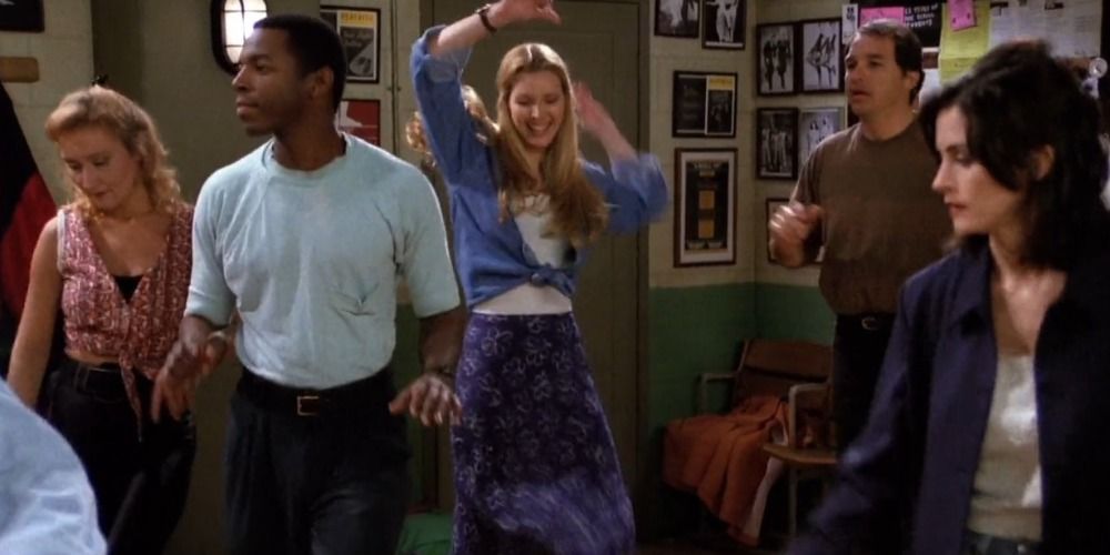 Phoebe smiling and dancing amongst the students at a tap dancing class in Friends