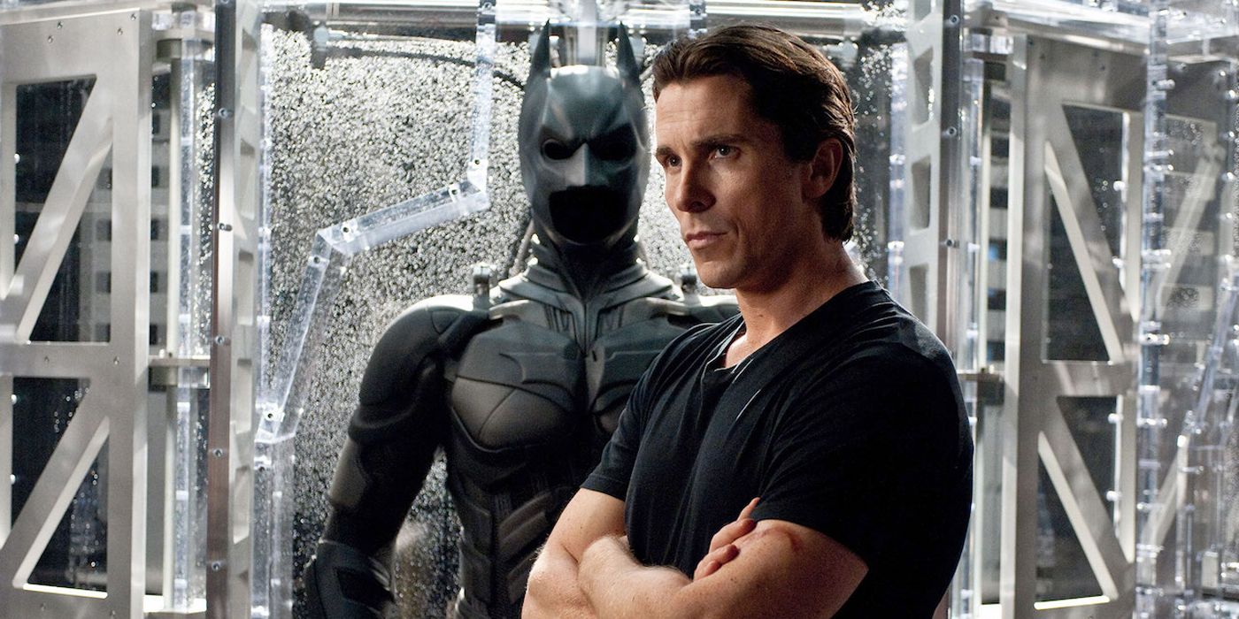 Christian Bale standing by the Batman suit