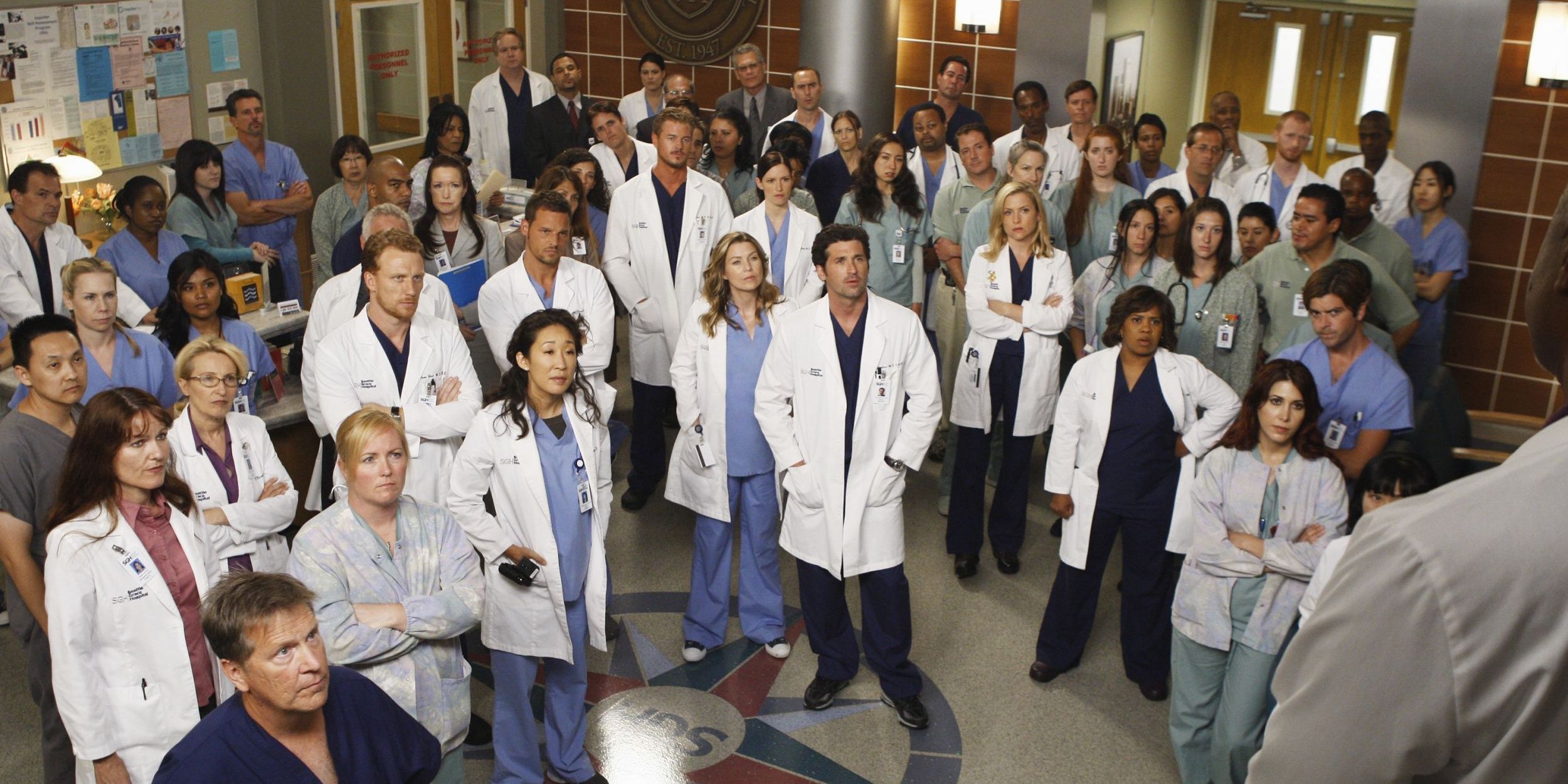 Hospital doctors stand around listening to an announcement in Greys Anatomy Cropped